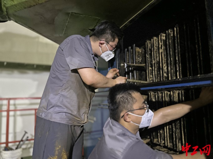 郭志浩（左）和同事一起紧固除尘滤袋固定卡螺栓 。  王盛斌  摄(1)