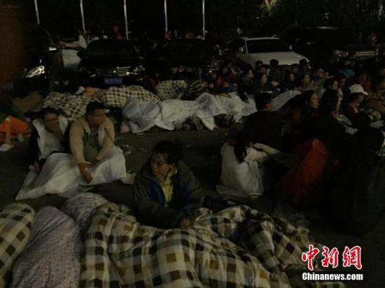 图为九寨沟景区内,许多游客不敢继续待在酒店内,裹着厚衣服和毛毯来到街上席地而睡。 徐广 摄