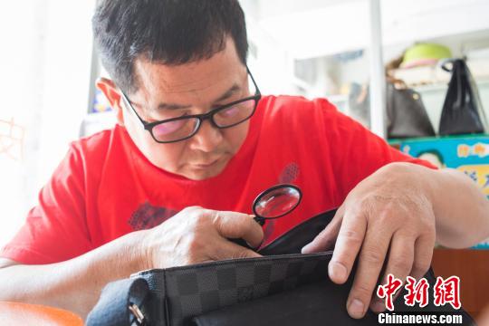 图为李文亮帮助客户辨别皮具真伪。 陈冠言 摄