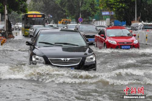 持续强降雨致使海口多条道路出现积水,车辆冒险缓慢通过如行船。骆云飞 摄