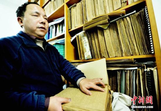 图为江西省德兴市盲人按摩医生马高亮正在触摸有关盲文医学书籍。卓忠伟 摄