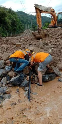 抢险人员配合抢险挖掘机清理塌方土石。