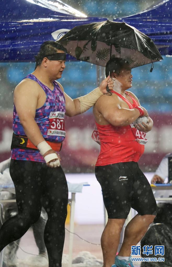 6月13日,新疆队选手陈剑(左)在比赛中为陕西队选手冯杰撑伞.