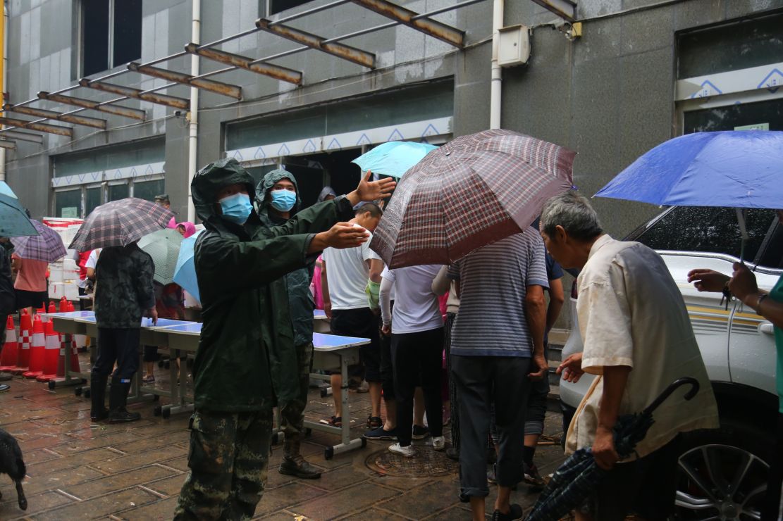 图为帮助政府工作人员维护临时安置点秩序。