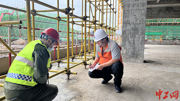 何维同志与负责安全的同事对施工现场脚手架搭设间距进行测量复查