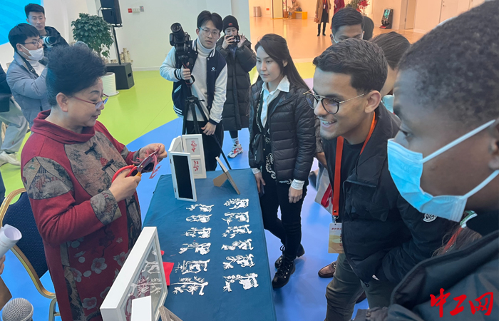 3月16日上午，在青岛·上合之珠博览中心的活动现场，留学生们与剪纸非遗传承人一起感受剪纸艺术的魅力。胶州市人社局供图