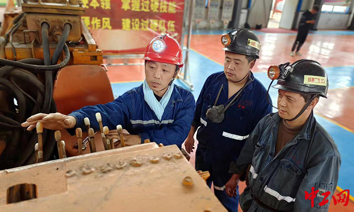 日前，徐爱斌（左一）和工友们交流智能综掘机技术。翟镇煤矿供图