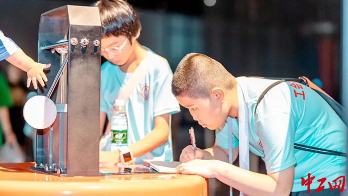 8月11日，在重庆科技馆宇航科技展厅，参与研学的孩子们认真做笔记。巴南区总工会供图