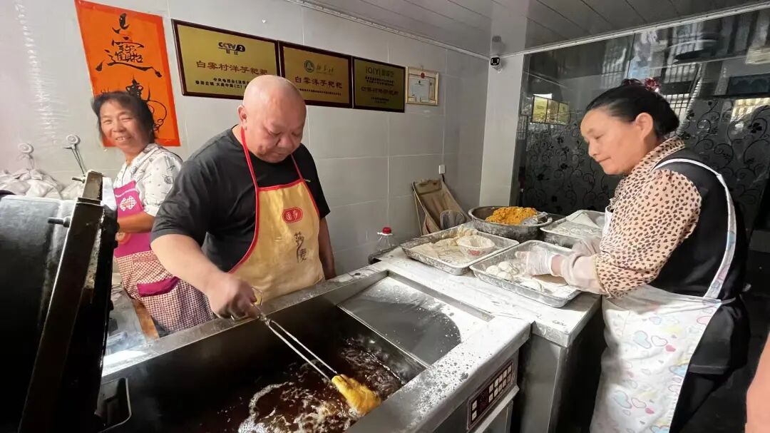 朱学贵（左二）在小吃店里炸洋芋粑粑